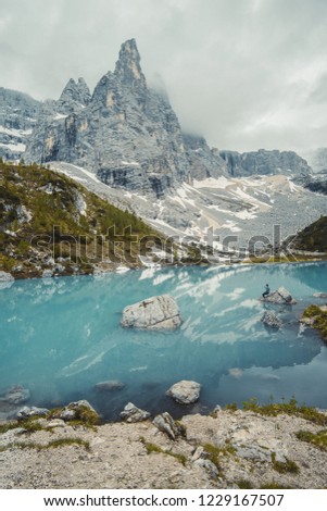 
Fantastic areial view into forest landscape. Lago di Sorapis with man on the rock looking on the mountain Dolomites, Italy, Europe.