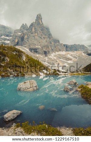 
Fantastic areial view into forest landscape. Lago di Sorapis with man on the rock looking on the mountain Dolomites, Italy, Europe.