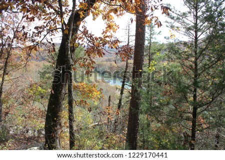 Beautiful picture of the Mulberry River in the distance from a cliff in the Ozark Mountains near The Pig Trail between Cass and Oark. Fall foliage visible in the foreground and background.