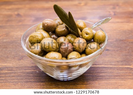 Bowl with olives and olive branch on a wooden table