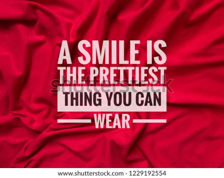 Inspirational motivation quotes on red fabric background. A smile is the prettiest thing you can wear.