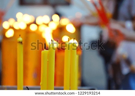 Flame from burning yellow candles at Chinese shrine for making merit theme background and texture or pray for Chinese Lunar New Year festival concept. (close up, selective focus, space for text)