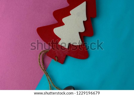Festive New Year's Christmas beautiful bright multi-colored joyful blue and pink background with a small toy wooden red and white cute Christmas tree. Flat lay. Top view. Holiday decorations.