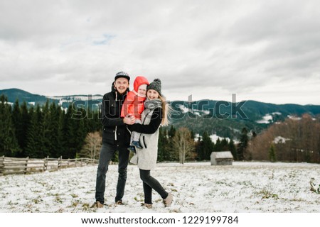 Happy family: mom, dad, girl are having fun and playing on snowy winter, walk in mountain, nature. Father, mother and children daughter enjoying journey. Frost winter season.