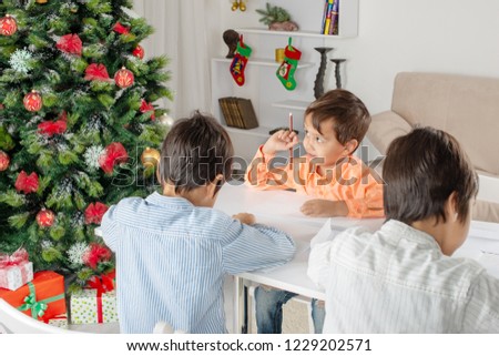 Children boys brothers or friends write the letter to Santa  Claus at Christmas tree.  