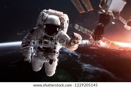 Astronaut at the Earth orbit with the Space station behind. Elements of this image furnished by NASA