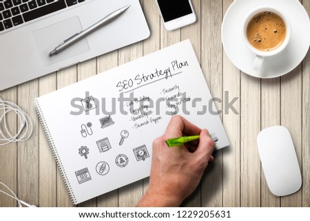 hand is writing a SEO strategy at a computer workplace