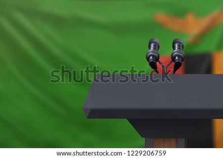 Podium lectern with two microphones and Zambia flag in background