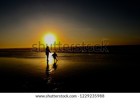 People on the beach at sunset. Yoga pose at sunrise. Silhouettes of a man and child at the ocean.