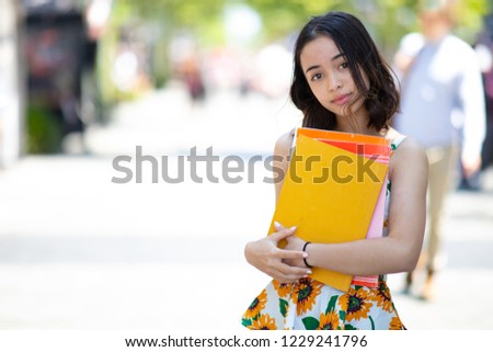 Young beautiful Caucasian women is holing text books with City background 