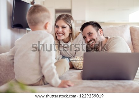 Portrait of a cheerful young family having fun together. They using laptop in living room.