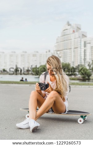 girl with long hair with skateboard photographing on camera. street, active sports