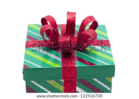 Close-up shot of bow of shiny ribbon on green gift box against white background.
