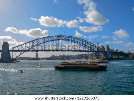 Side view of Sydney Harbor Bridge with ferry boat passing in front of the bridge