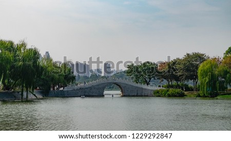 White stone footbridge in an Chinese garden lacated among the modern building. Wuhan, Hubei China.
