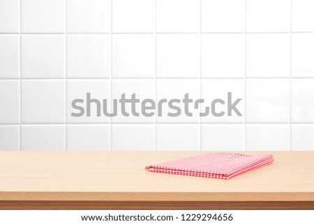 Empty wooden table with tablecloth over white tile wall. Background for advertise product.