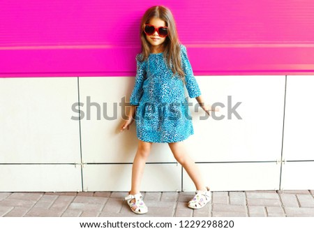 Fashion little girl posing in leopard print dress on colorful pink wall background