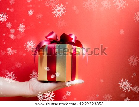 Valentine festival , New year Gold gift box with red ribbon. Red background for create idea copy space.hand holding gift box