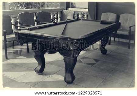 Beautiful photo of stylish pool table with a cue and billiard balls on a nice patio. Snooker. Black & White Photography. Old photo. Stunning vintage. Retro. Stylish postcard.