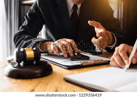 justice and law concept.Male judge in a courtroom  the gavel, working with smart phone and laptop and digital tablet computer on wood table in morning light 

