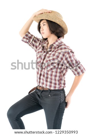Young pretty woman in a cowboy hat and plaid shirt with hand on her hat isolated on white background