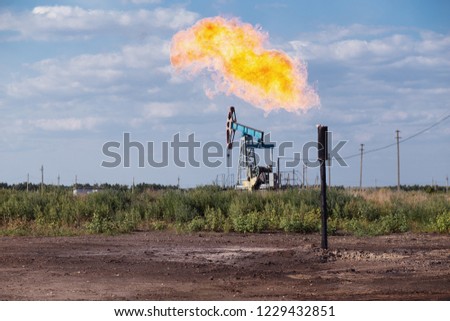 Oil pumpjack and gas torch on oil production Royalty-Free Stock Photo #1229432851