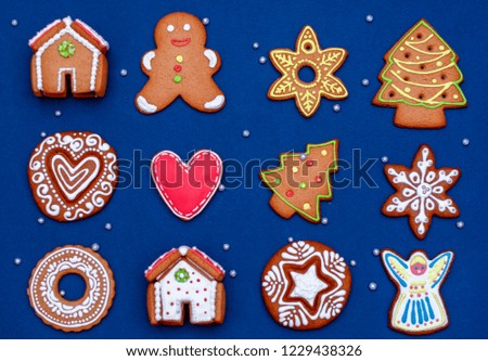 Christmas cookies with painted glaze of different shapes laid out on a blue background