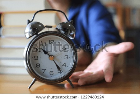 Close-up of hands holding ancient clock in library. Book stack is the background selective focus and shallow depth of field
