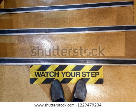 Top view of feet on watching sign yellow drawn watch your step