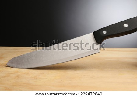 Chef knife on a wooden block in dark background. Silver steel big knife. Simple image of knife. Minimalistic style.  Royalty-Free Stock Photo #1229479840