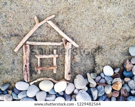 Image of a little house from wooden sticks on the sea pebble beach. Sea tour. Concept image house. Concept of sale or purchase house