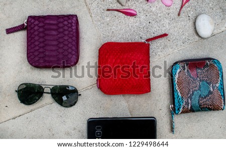 Exotic and luxury set of hand made leather wallet . Multi colored. Leather craft. On a stone tile with background with Plumeria . Python snake fashionable handbag, purse, clutch. Python accessories