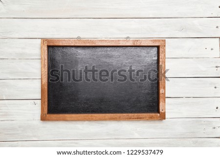 Blackboard in wooden frame on white wooden table. Top view copy space.