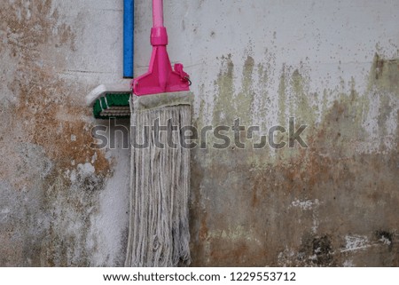 mop and hard floor brushes hanging from the walls of houses with stains on the walls.