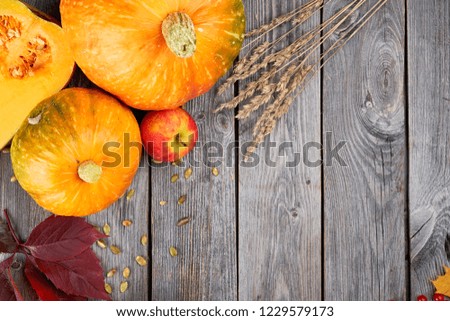 Autumn harvest Thanksgiving pumpkins, apples, wheat ears and fallen leaves on wooden background. Top view with copy space. Seasonal Fall Food.