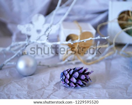  Festive Christmas decorations of purple cones, white branches, silver ball, gifts on a light background, seasonal winter celebrations
