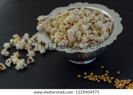 popcorn and popcorn grains in copper pot on black wooden table
