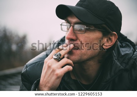 A man smokes a cigarette. Guy with glasses smokes cigarettes. Tobacco smoke
