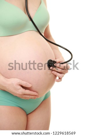  pregnant woman wearing green bras and panties examining belly with stethoscope