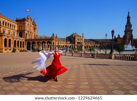 Flamenco dancer in red dress and white spanish shawl dancing on Plaza de Espana during Feria de Abril (april fair) in Seville, Spain Royalty-Free Stock Photo #1229624665