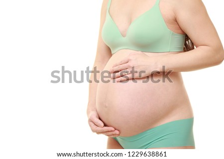 pregnant woman wearing green bras and panties touching her belly 