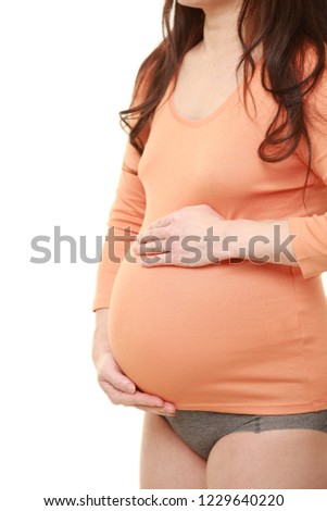 pregnant woman wearing orange shirt with gray panties touching her belly 