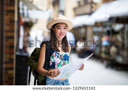 Young beautiful women walking in the city for sightseeing in City of Perth, Australia. She is holding a map and carry on backpack looking at the map and enjoy her holiday.