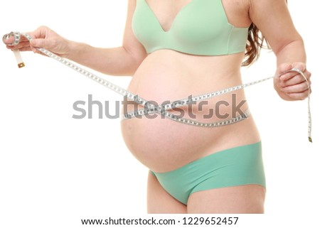 pregnant woman wearing green bras and panties measuring her stomach