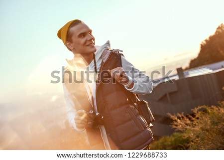The silhouette of a young man standing alone on a sunrise background in the morning with camera