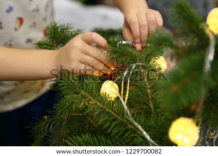 Close-up of child hanging decorative toy ball on Christmas tree branch
