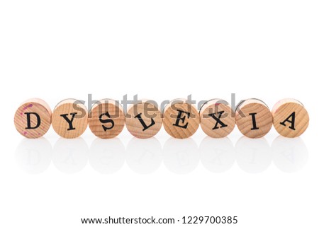 Word Dyslexia from circular wooden tiles with letters children toy. Concept of learning difficulty disorder spelled in children toy letters.