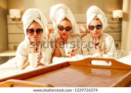 Three rich young girls on bed and wooden tray of free space for your decoration. 