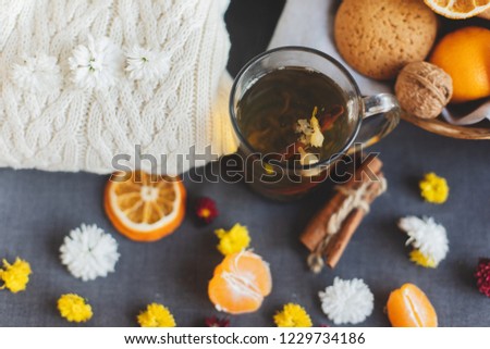 Tangerines, flowers, gingerbread, citrus in sraw basket, warm sweater, cup of tea and orange slices. Christmas winter background, wallpaper, greeting card. Top view, flat lay, background, copy spaces
