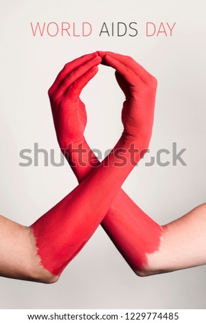closeup of the arms of two men painted red forming a red awareness ribbon and the text world aids day against an off-white background Royalty-Free Stock Photo #1229774485